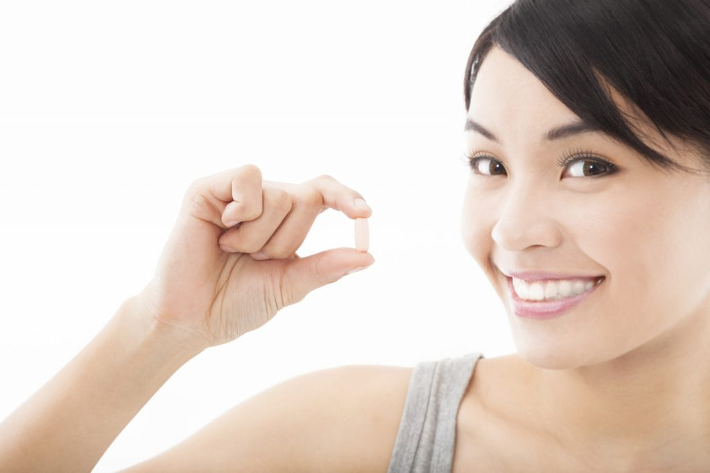 smiling woman holding pill of high supplement quality