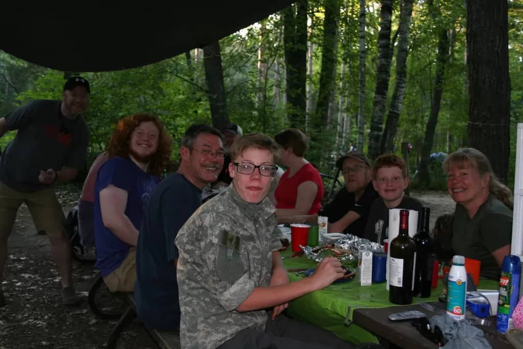 picture of a family eating dinner at a picnic table while group camping