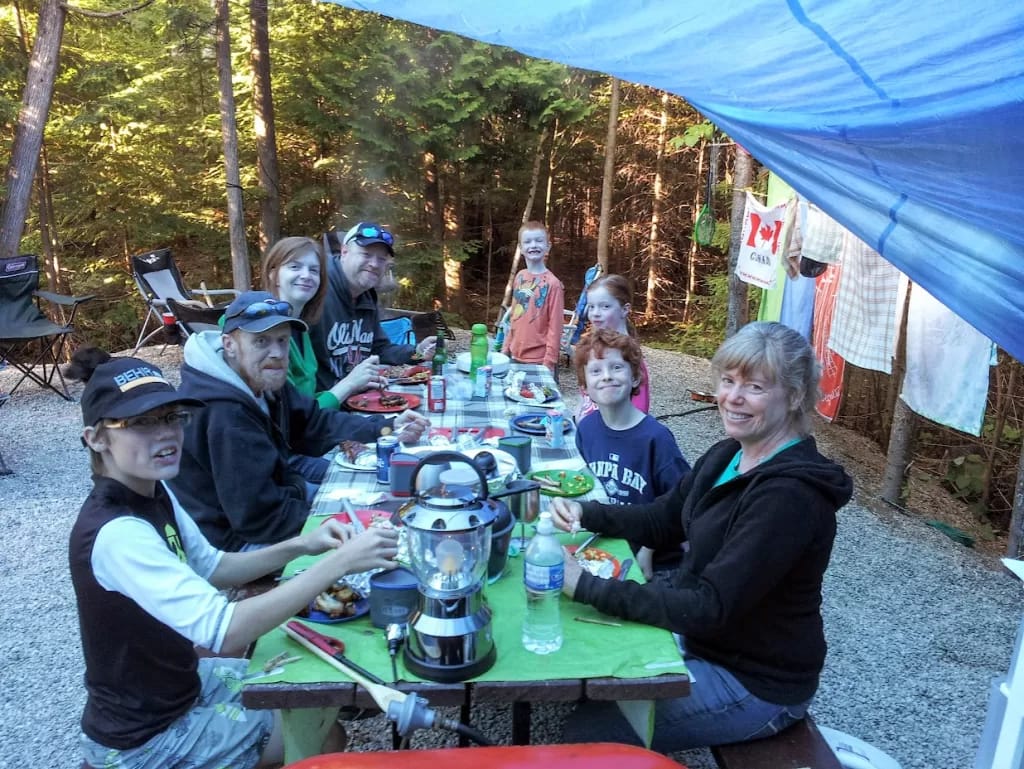 picture of a family eating at a picnic table while group camping