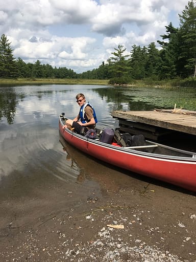 picture of Thomas in a red Scott fiberglass canoe at Kawartha Highlands Provincial Park backcountry camping