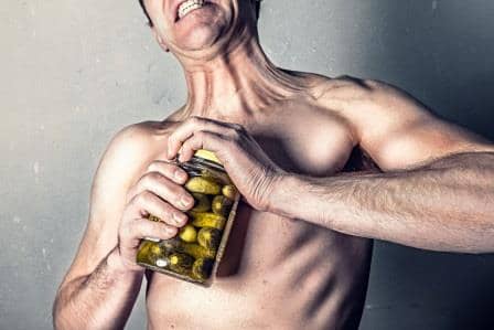 man straining to open pickle jar with prominent tendons made from collagen
