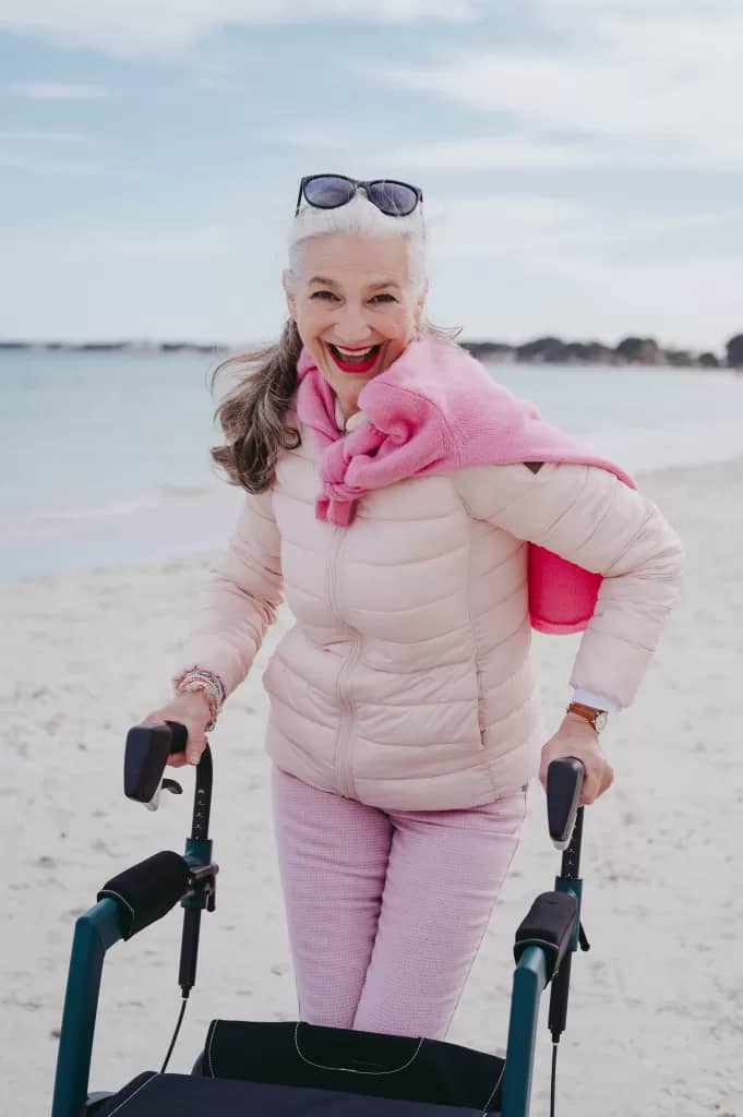 picture of a woman with mobility challenges walking on the beach with the use of a walker